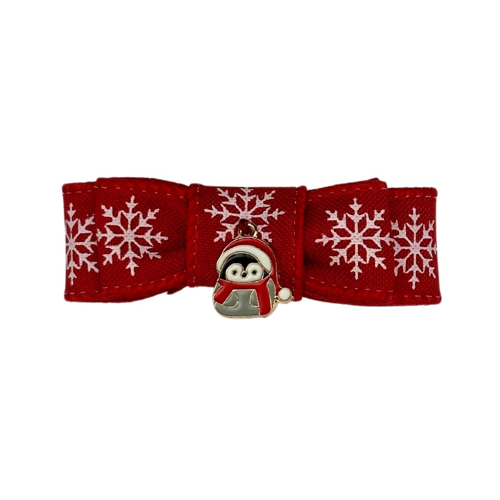 Holiday red cat collar bow with white snowflakes and a penguin charm in a scarf. Handcrafted festive pet accessory by Beloved Lily's Pet Company.