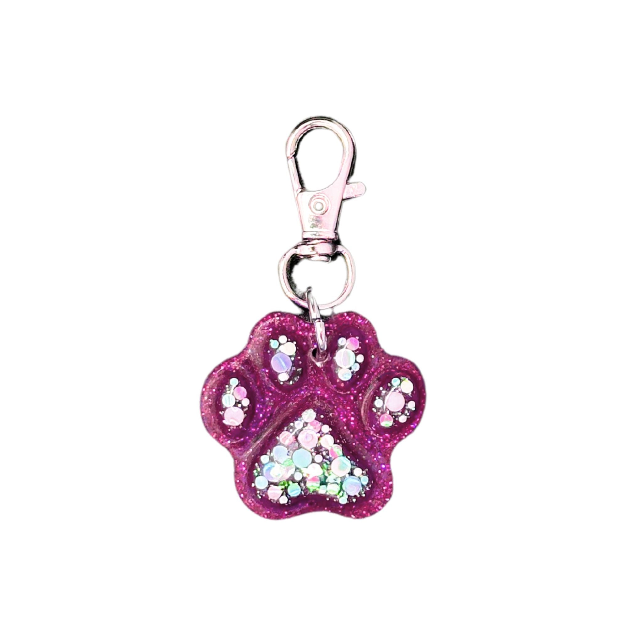 “Glittering paw print-shaped pet ID tag crafted from purple resin, featuring a colorful glitter accent and a scannable QR code for easy pet identification.”